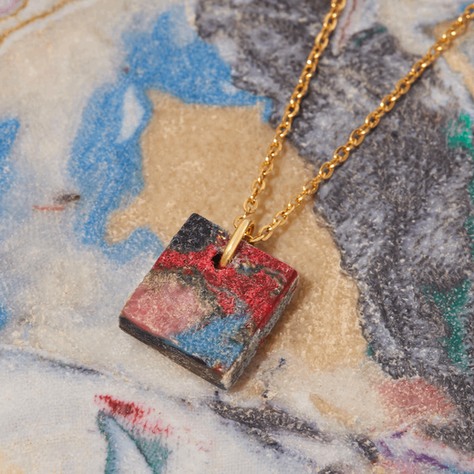 A square shaped pendant in swirling multicolour shades on a background of the same pattern.